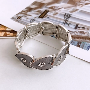 Detailed macro of vintage silver heart bracelet with embossed flower patterns