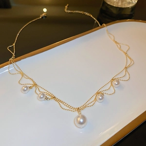 Detailed view of layered gold plated pearl necklace in a white ceramic tray