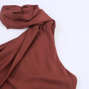 Détail macro du tissu en soie marron foncé lisse avec un décolleté plissé élégant