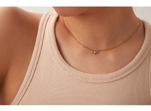 Model wearing a delicate 18k gold clover necklace with sparkling white zircons