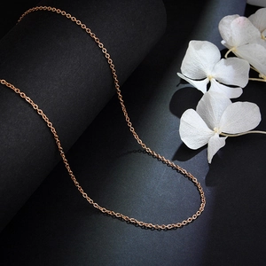 Elegant rose gold titanium steel link chain necklace on dark textured background with flowers