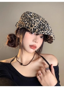 Macro detail of retro leopard print newsboy cap fabric with vintage beaded jewelry