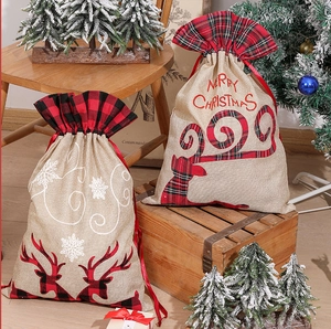 Detail of burlap Christmas drawstring bags with reindeer and snowflake motifs on wooden stools