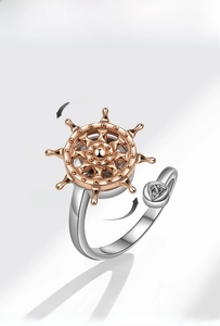 Macro detail of nautical spinning ring featuring rotating golden ship wheel design