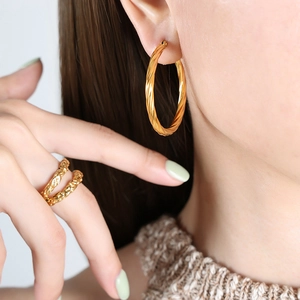 Minimalist gold twist hoop earrings and hammered rings set on model for a chic look