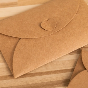 Vintage brown kraft paper envelope with unique heart-shaped closure on a wooden desk