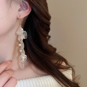 Macro detail of elegant pearlescent resin flower earrings with gold hooks on model