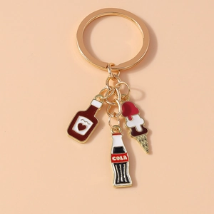Close-up of gold metal keychain featuring cola bottle, ice cream, and heart bottle charms