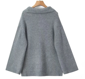 Detailed close-up of grey knit sweater showing vertical rib texture and oversized cuffs