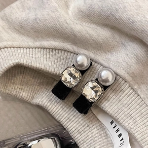 Vue détaillée de barrettes à cheveux rétro avec perles et cristaux sur un pull gris