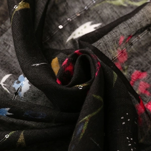 Detailed macro view of black linen scarf with colorful floral print and silver sequins