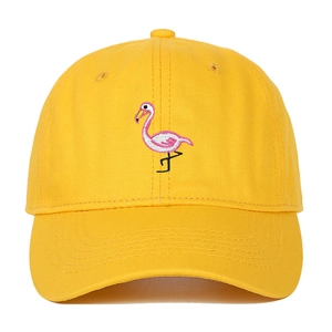 Close-up of pink flamingo embroidery detail on a yellow cotton baseball cap