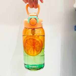 Detail of a large gradient Tritan water bottle showing the durable orange carrying handle