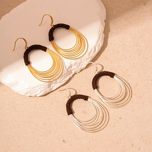 Exaggerated multi-layer hoop earrings in gold and silver with fabric-wrapped detailing
