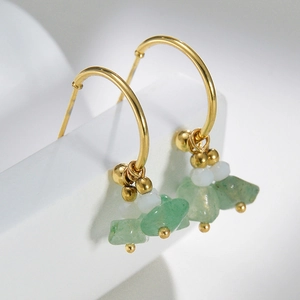 Macro shot of 14k gold C-shaped earrings with green natural stone and white beads