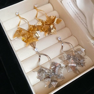Detailed macro view of hollow leaf tassel earrings with gold and silver finish