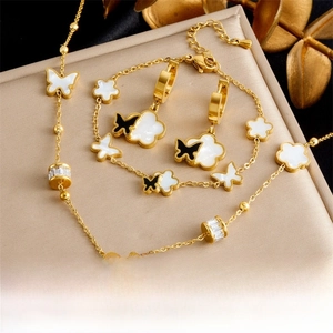 Detail view of gold butterfly and flower jewelry set with black and white enamel inlays