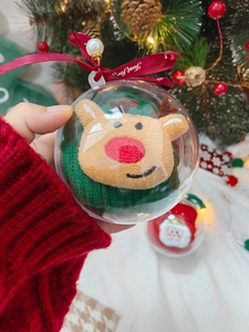 Weihnachtskugel mit Plüsch-Rentier und rotem Band in der Hand gehalten