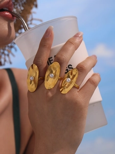 Close-up of gold PVD steel ring with oval shell pearl on model's hand against blue sky
