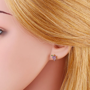 Close-up of purple and green rhinestone grape stud earrings with golden metal base