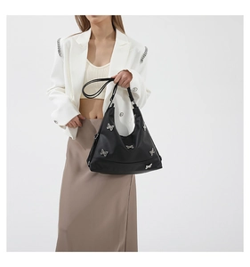 Detail of black tote bag featuring silver butterfly patterns and sleek glossy finish