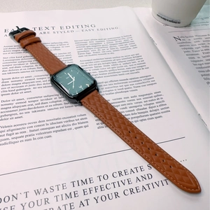 Detail of square quartz watch with brown quilted leather strap on an English magazine