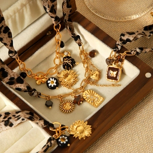 Golden multilayer necklace with leopard print ribbon and floral charms in a wooden box