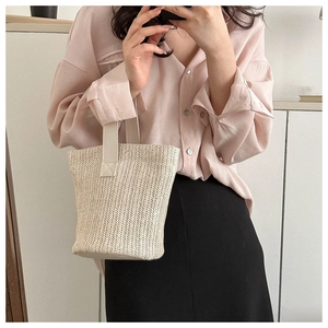 Close-up of a handmade straw bucket bag with elegant woven texture and cream handle