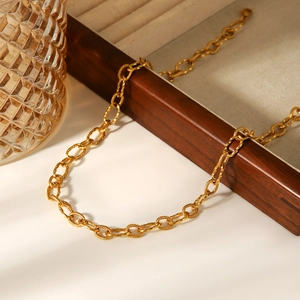 Collier chaîne en acier inoxydable doré 18 carats sur un plateau à bijoux en bois chic
