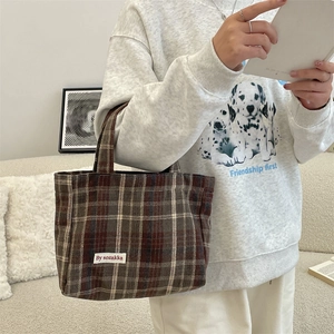 Detail of vintage plaid canvas handbag with By sozakka label in a casual lifestyle setting