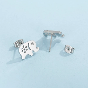 Gros plan des boucles d'oreilles éléphant en argent avec détails sur fond bleu clair