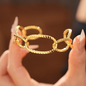 Close-up of gold-plated twisted rope chain cuff bracelet with high-shine metallic finish