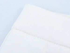 Detail of white trousers showing high-quality stitching and smooth fabric texture