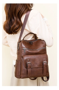 Detailed view of vintage dark brown faux leather backpack with retro buckle on a model