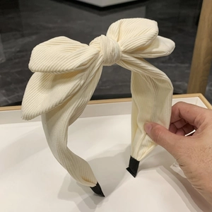Plush cream corduroy headband featuring a large bow design for a high-volume look