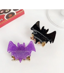 Detail of glittery bat-shaped hair claws in black and purple with golden metal clips