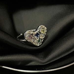 Detail of silver butterfly textured ring with colorful gems on black silk background
