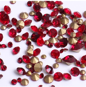 Macro shot of sparkling deep red and gold faceted nail art rhinestones on white background