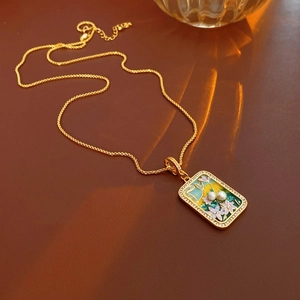 Detail of vintage gold necklace featuring enamel flower and pearl pendant on leather