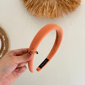 Détail du serre-tête éponge tricoté fait main en rose orangé avec texture douce