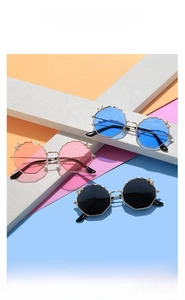 Détail des bords festonnés et des nœuds dorés sur les lunettes de soleil enfant