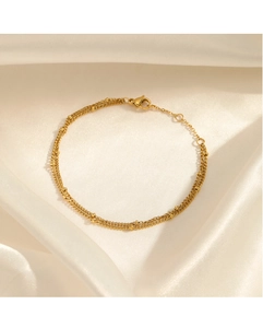 Detail of double-layer gold beaded bracelet on white silk with adjustable lobster clasp