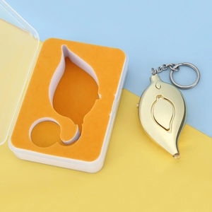 Detailed view of leaf-shaped personal alarm in gold with key chain in gift packaging