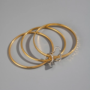 Detailed view of 18K gold plated triple-layer bracelet with silver heart-shaped charm
