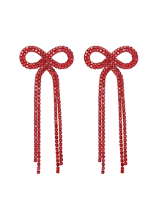 Macro shot of red rhinestone bow earrings with long tassels on a white background