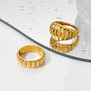 Polished gold-plated stainless steel wide ring featuring a textured vertical wave pattern