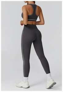 Detail showing the racerback structure and side white stripes of the charcoal sports bra