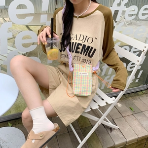 Detailed view of mini checkered phone bag with orange rope strap worn by model