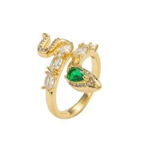 Golden snake ring with green emerald zircon and white stones on white background