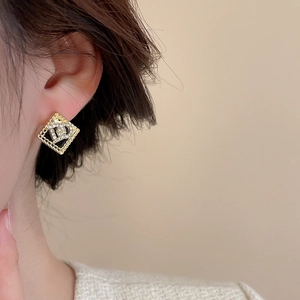 Close-up of vintage square gold earrings with black inlay and crystal flower pattern